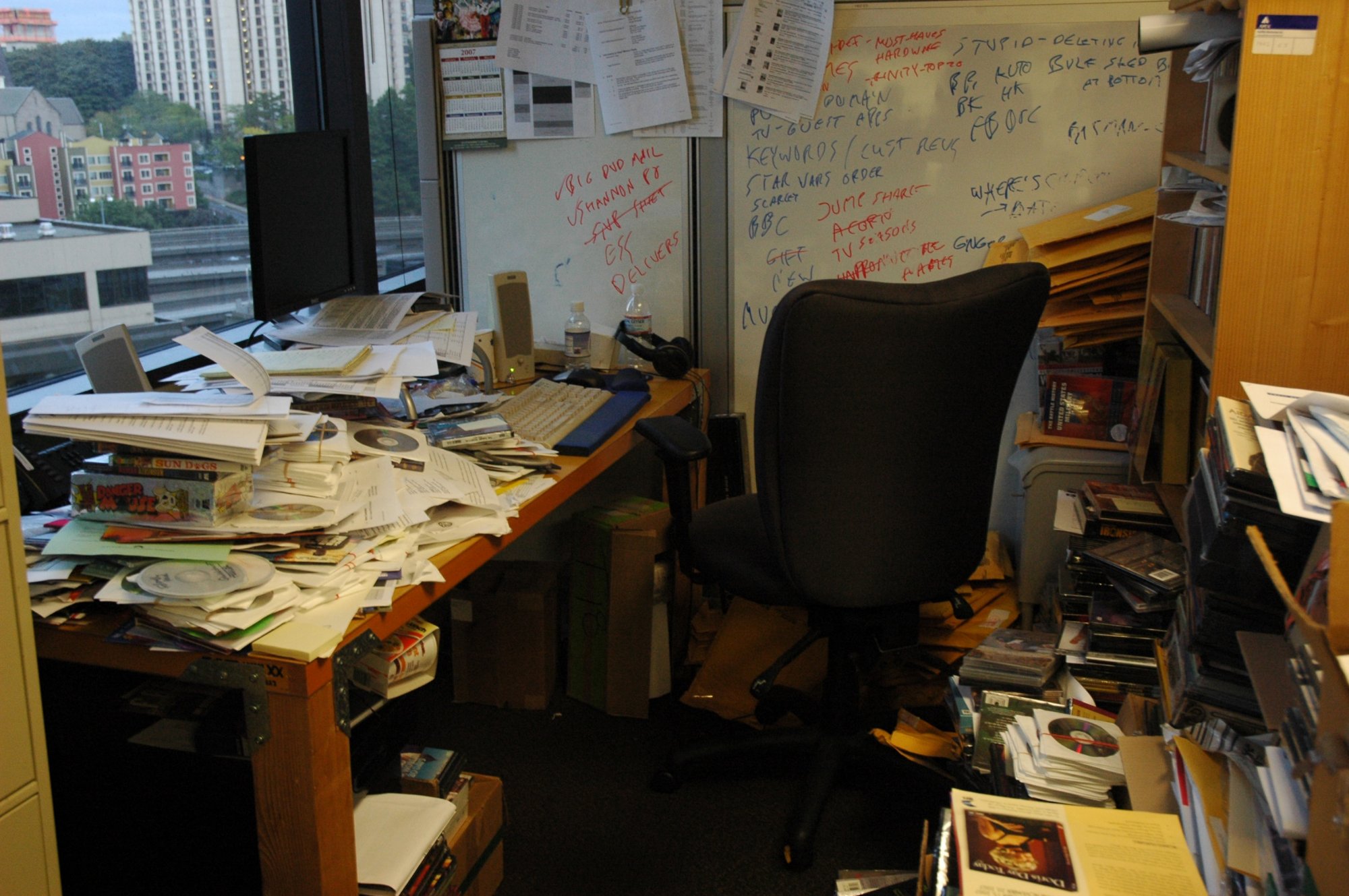 A messy office and desk with paper and chaos everywhere.