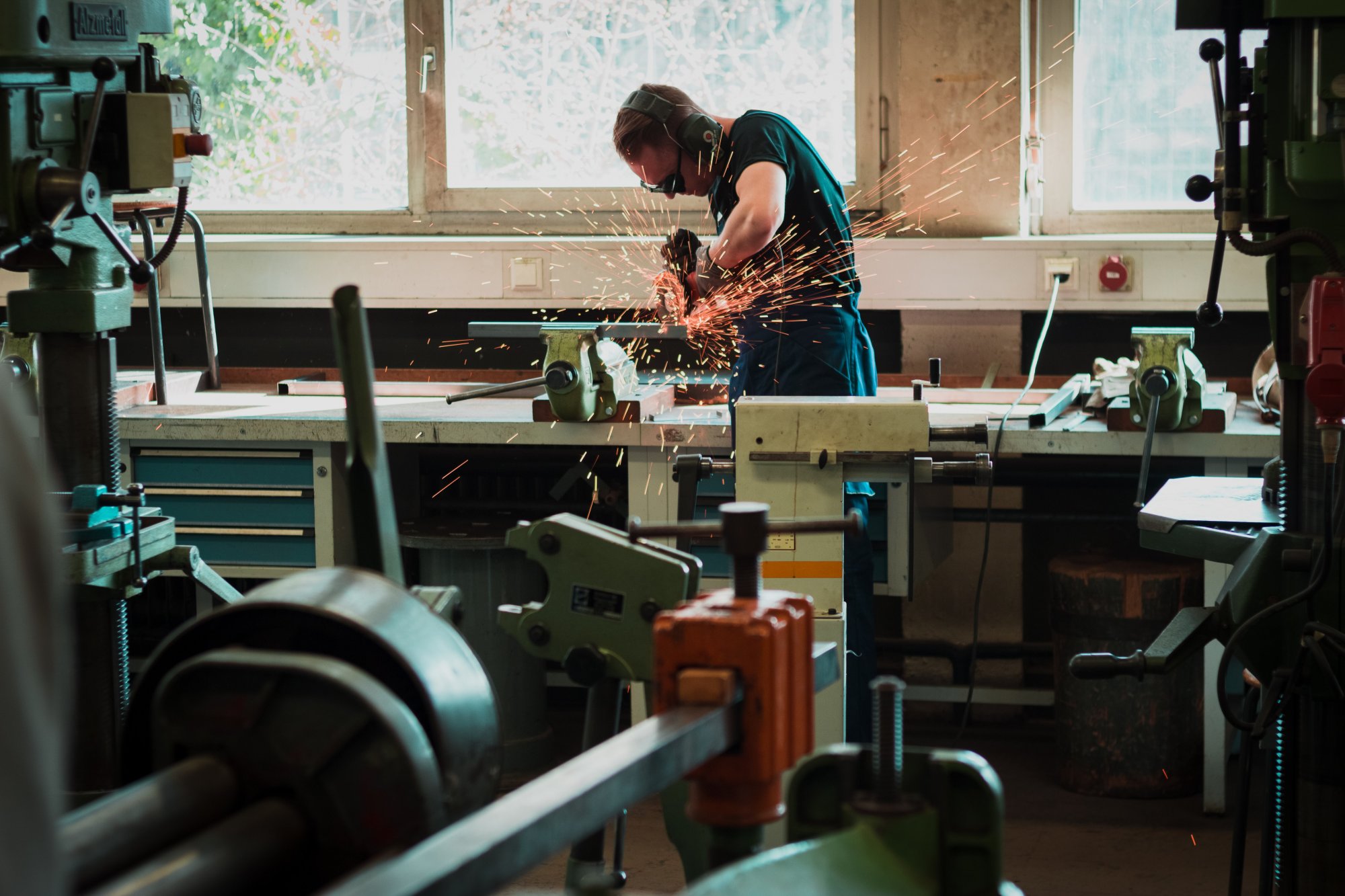 A man grinding metal on a workbench.