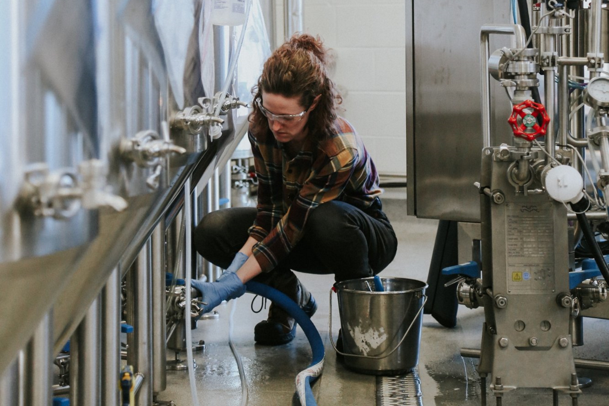 A woman adjusting valves on a family run brewing business.