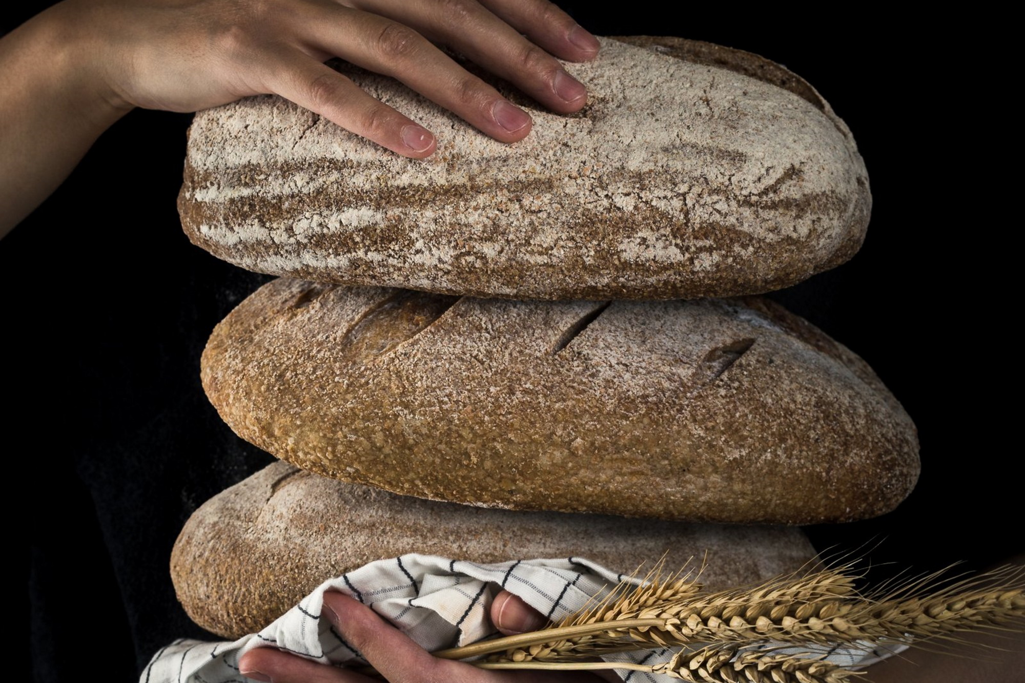 A baker holding stacked loaves of round bread.
